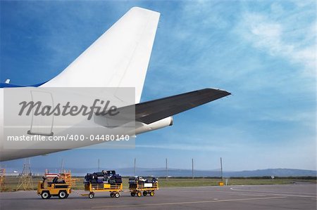 airplain tale and luggage cart on the airfield, preparing to depart