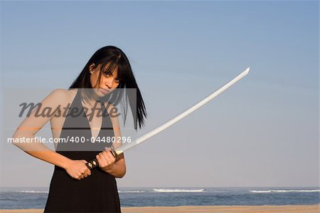 Asian model posing with a sword against blue sky