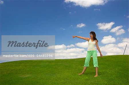 Beautiful young woman on a green meadow showing something