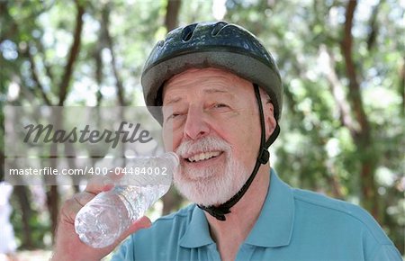 A senior man taking a water break after riding his bike.