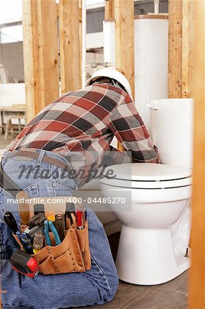 A plumber installing fixtures in new construction.  Focus on his tool pouch.