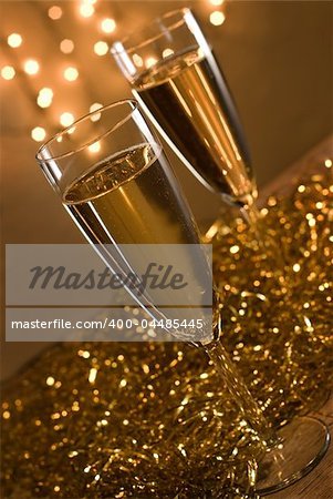 Two champagne flutes, defocused christmas lights on the background - shallow DOF, focus on the first glass.