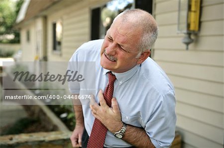A mature businessman doubled over clutching his chest.  He appears to be having a heart attack.