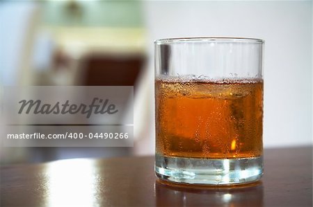 The misted over glass of whisky with an ice on a table