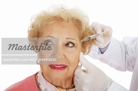 Senior woman having cosmetic surgery injections to fill in wrinkles around eyes.  White background.