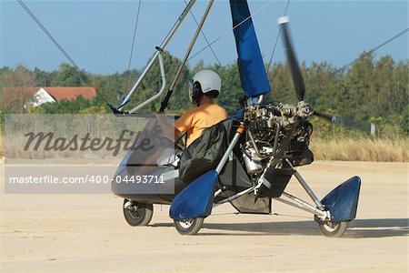 Microlight airplane taxiing down a dirt runway at an airfield