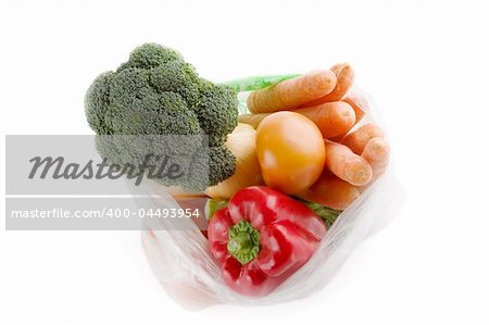 Healthy vegetables in a clear plastic grocery bag on a white background