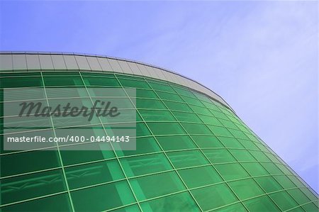 large building of green glass rising in the clear blue sky