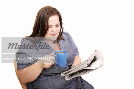 Beautiful plus-sized woman reading the newspaper and drinking coffee.  Isolated on white.