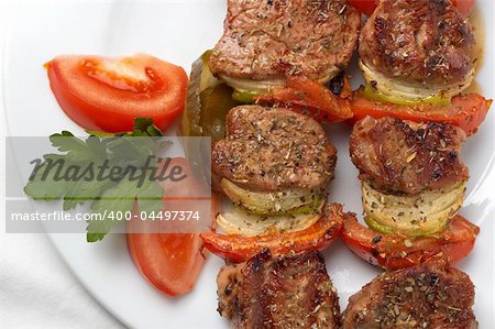 kebab served with vegetables on white plate, closeup