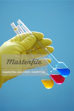 yellow glove holding chemical liquids in flasks