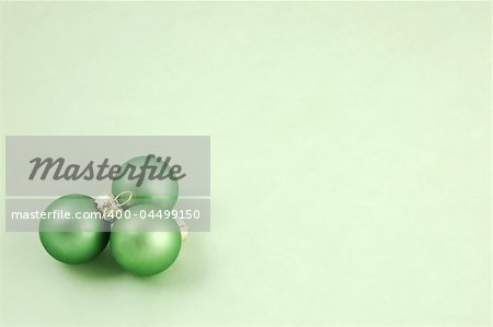 Green Christmas ornaments on a pale green background with copyspace
