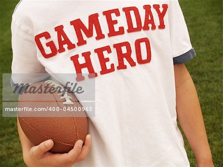 male holding an American football and wearing a "Gameday Hero" shirt