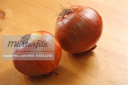 Two whole raw onions on wooden background
