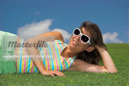 Beautiful young woman on a green meadow with a flower