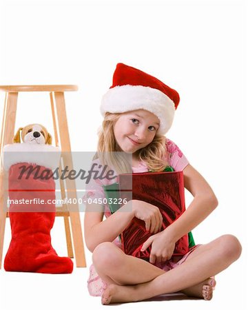 cute little eight year old girl sitting on floor holding red wrapped christmas presents