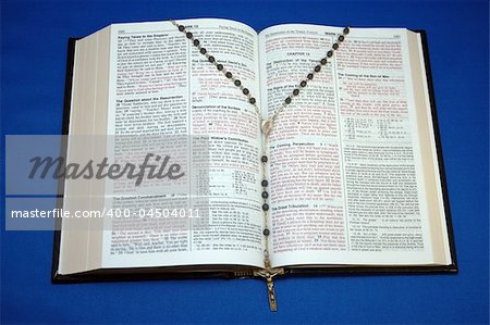 Holy bible on blue background with rosary