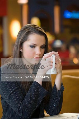 young woman looking sad warming herself with e hot cup of tea