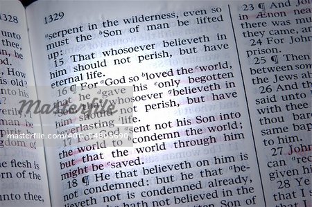 Bible is opened to John 3:16, highlighted by a beam of light.