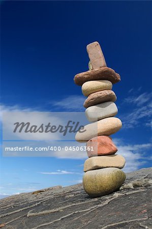 Column of balanced boulders against blue sky