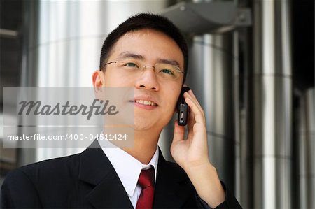 Young asian executive talking on a handphone dressed in suit.
