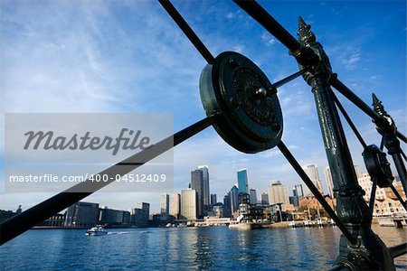 View of Sydney Cove from behind decorative iron railing with city skyline and water in Sydney, Australia.