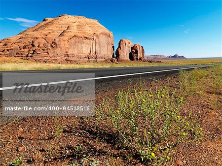 Road in scenic desert landscape with butte land formation.