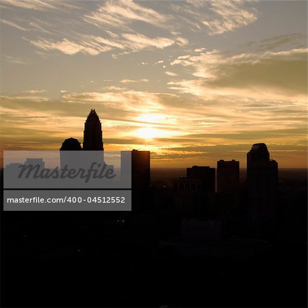 Sunset silhouetting aerial view of Charlotte, North Carolina city skyline.