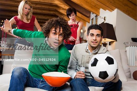 domestic life: group of friend watching soccer on tv while their girlfriends are disappointed