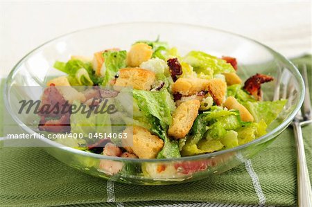 Fresh caesar salad with croutons and bacon bits served in a glass bowl