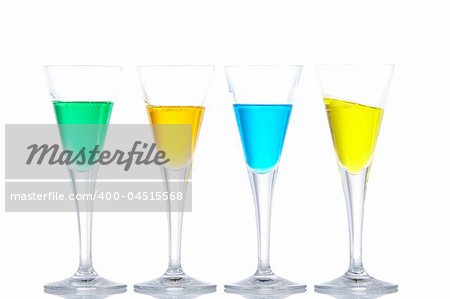 Four glasses with beverages, reflected on white background. Yellow on angle. Shallow depth of field
