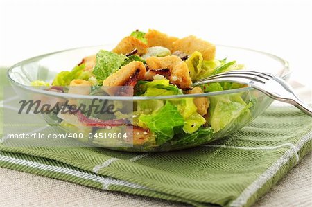 Fresh caesar salad with croutons and bacon bits served in a glass bowl