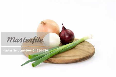 Different sorts of onions on a wooden kitchen board