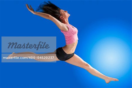 a cute gymnast in a hard jump on a blue background