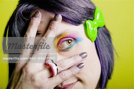 Close-up of a woman with bright mascara hiding her eye behind her hand.