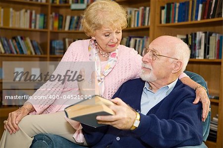 Senior man and woman reading together and discussing.