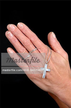 Woman is praying holding her cross. On black clean background.