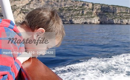 little boy looking over the railing on a boat