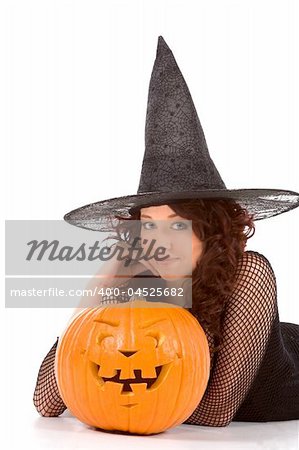 Portrait of Hispanic teenager girl in black Halloween hat and fishnet dress with carved pumpkin (Jack O' Lantern)