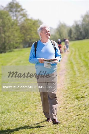 Man walking outdoors holding map smiling with people in backgrou