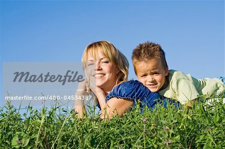 Boy outdoors on the grass with his mother in summer time