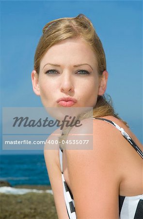 Beauty model Chrissy at Laguna Beach, CA. She wears a black and white sundress. She poses in a classic, Marilyn Monroe kiss to the camera.