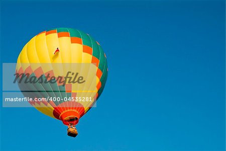 A colorful hot air balloon floating in a bright blue sky.