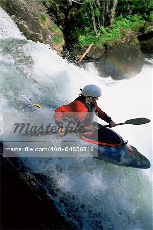 Young woman kayaking down waterfall