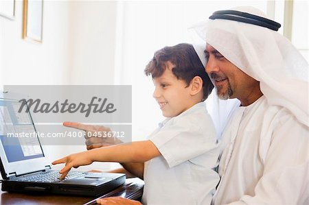 A Middle Eastern man and his son sitting in front of a computer