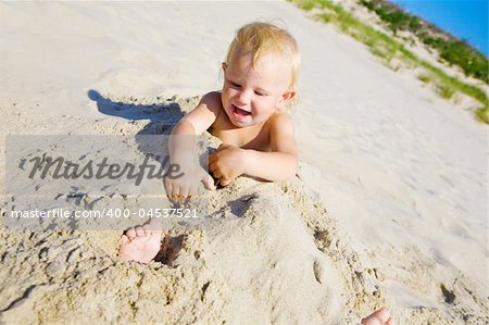 Young girl buried in the sand smiling at camera