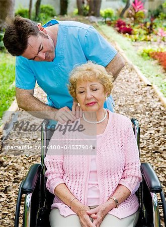 Senior woman in wheelchair receives massage therapy from a physical therapist.
