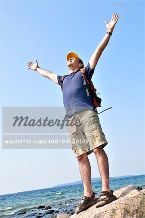 Middle aged hiker standing on top of a mountain raising his arms
