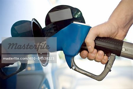 close-up of a mens hand refilling the car with a gas pump