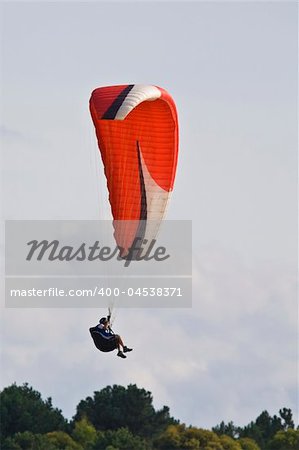 A man with a colorful paraglider flying in the sky